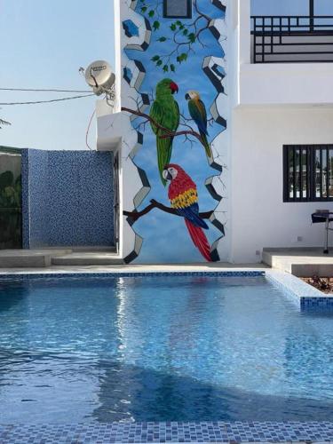 a mural of two birds on a tree branch next to a swimming pool at Ecolodge La Grande Tortue - Maison d'hôtes in Toubab Dialaw