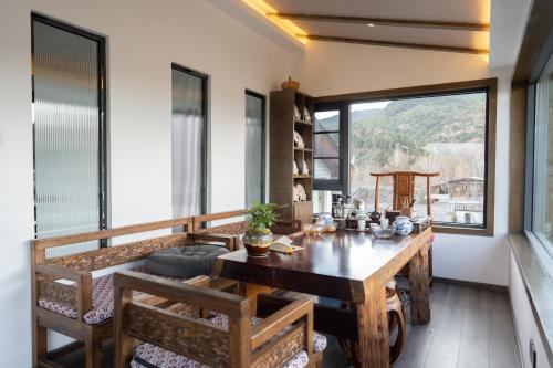 a dining room with a table and a large window at 清舍雪山观景设计师民宿 in Lijiang