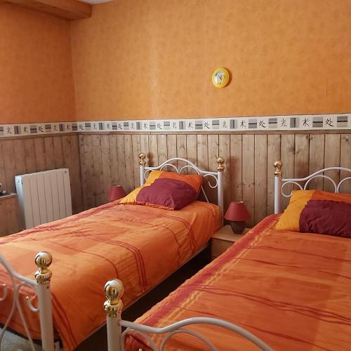 - une chambre avec 2 lits avec des draps orange et une horloge murale dans l'établissement appartement chez Chantal RDC 60m2 GERARDMER, à Gérardmer