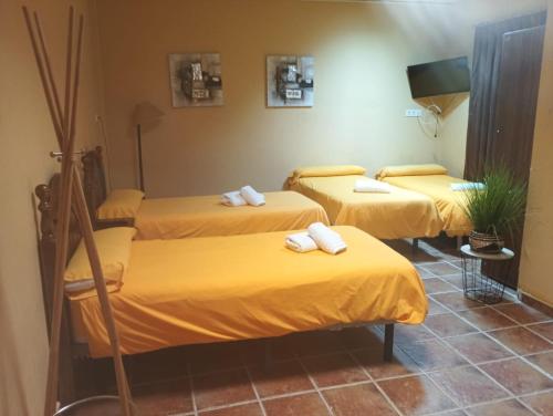 three beds in a room with yellow sheets at Complejo Rural Las Lomas de Biar in Biar
