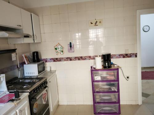a kitchen with a purple shelf in the corner at heart of marsa beach in Douar el Hafey
