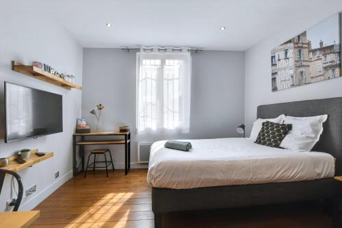 - une chambre avec un lit, une télévision et un bureau dans l'établissement Le Boubée - Studio proche gare, à Toulouse