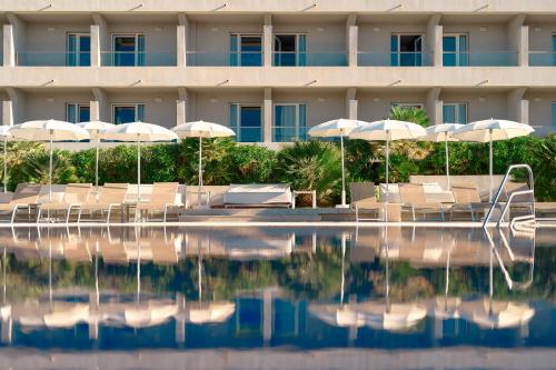 a hotel with chairs and umbrellas and a swimming pool at Pharos Hvar Bayhill Hotel in Hvar