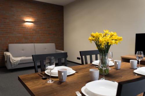 a wooden table with a vase of yellow flowers on it at Apartamenty Pod Grojcem - Dream Apart in Żywiec