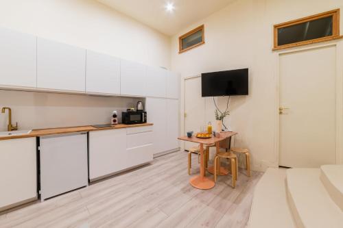 une cuisine avec des armoires blanches et une table dans une pièce dans l'établissement Charmant appartement moderne haut marais - 4P, à Paris