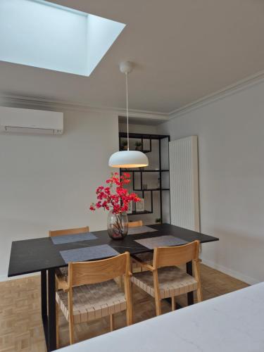 a dining room with a table with chairs and a vase of flowers at Huis ALNA 8 in Mechelen