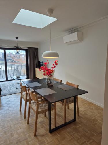 a dining room table with a vase of flowers on it at Huis ALNA 8 in Mechelen
