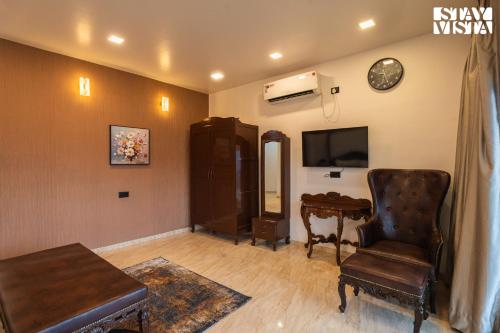 a living room with a chair a table and a tv at StayVista at Auburn Dusk with BBQ & Pool in Panchgani