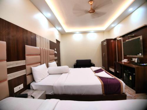 a hotel room with two beds and a tv at Elegant Beach Resort in Mandarmoni