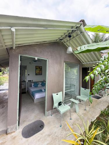 1 cama y sillas en un patio con 1 dormitorio en KA Surf Hostel, en Ahangama