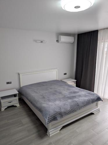 a white bedroom with a bed and two tables at Ізумруд in Chop