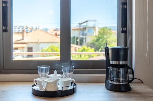 a coffee maker and cups on a table with a window at Petrino Serene Studios in Kakóvatos