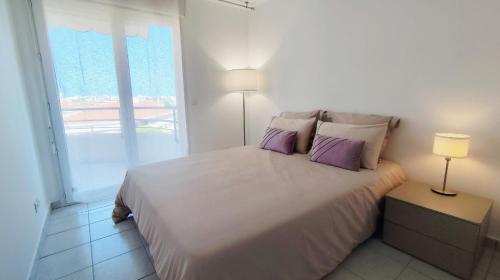une chambre avec un grand lit blanc avec des oreillers violets dans l'établissement Elegant Apartment with Private Pool, Parking & 5min to beach, à Antibes