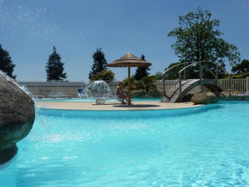 - un parc aquatique avec une fontaine et un parasol dans l'établissement Camping Paradis Domaine de Bel Air, à Landudec