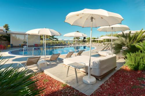 a patio with chairs and umbrellas and a pool at Pharos Hvar Bayhill Hotel in Hvar