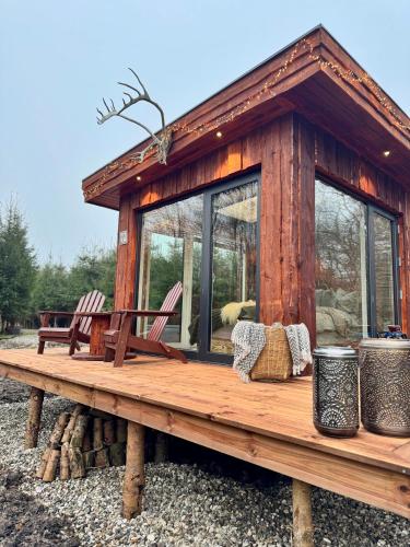 a wooden cabin with chairs on a table at Heart of Nature - Luksus Glamping & Spa in Nørre Hvalsø