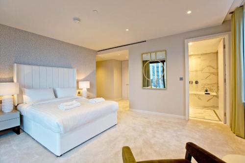 a bedroom with a large white bed and a bathroom at Luxury Living with City Views with Pool and Gym AC in London