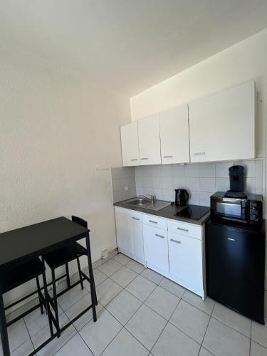une cuisine avec des placards blancs et une table noire dans l'établissement Foch 7-Proche Allée Paul Riquet-wifi-tv connectée, à Béziers