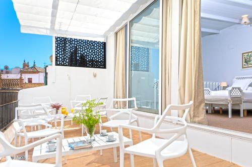 een kamer met witte stoelen en een groot raam bij Genteel Home Mateos Gago Terrace VI in Sevilla
