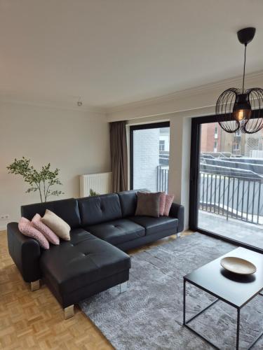 a living room with a black couch and a large window at Huis ALNA 8 in Mechelen
