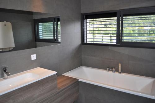 une salle de bain avec deux lavabos et deux fenêtres dans l'établissement L'Ecrin Contemporain, à Nages-et-Solorgues