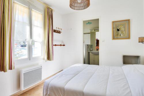 a white bedroom with a bed and a window at Maison pour 7 à 900m de la plage avec jardin in Barbâtre