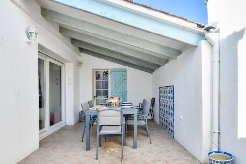une salle à manger avec une table et des chaises sur un patio dans l'établissement Maison pour 7 à 900m de la plage avec jardin, à Barbâtre