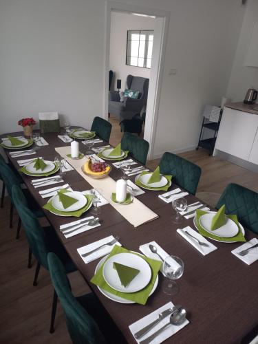 a long table with green plates and silverware on it at Cityhouse Lubliniec 4 Bedrooms, Garden, Parking, Business & Family in Lubliniec