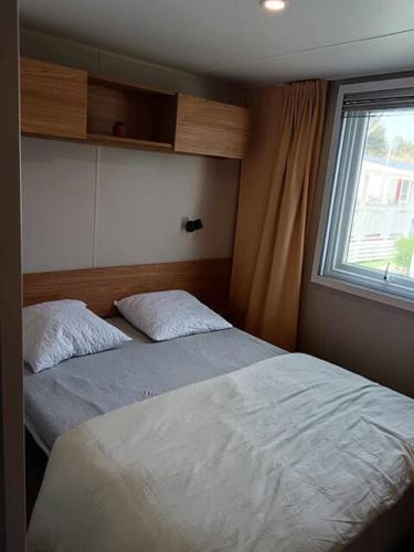 une chambre avec deux lits et une fenêtre dans l'établissement Mobil Home Bouginvilliers 2, à Valras-Plage