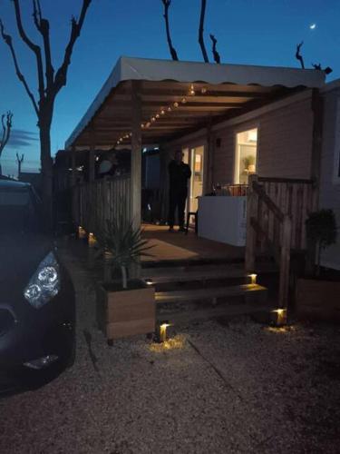 un homme debout devant une maison la nuit dans l'établissement Mobil Home Bouginvilliers 2, à Valras-Plage