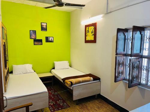 a room with two beds and a green wall at YOU and I CAFE in Varanasi