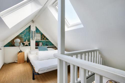 - une chambre mansardée avec des murs blancs et des lucarnes dans l'établissement Appartement pour 4 à 200m de la plage du Prieuré, à Dinard
