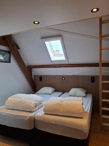 two beds in a attic room with a window at Tsjaka+ in Ronse