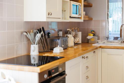 a kitchen with white cabinets and a counter top at The Old Abbey Farmhouse - Stay at Quarr Abbey Monastery - Pet-Friendly Farmhouse with History & Countryside Views, surrounded by woodland & nature in Ryde
