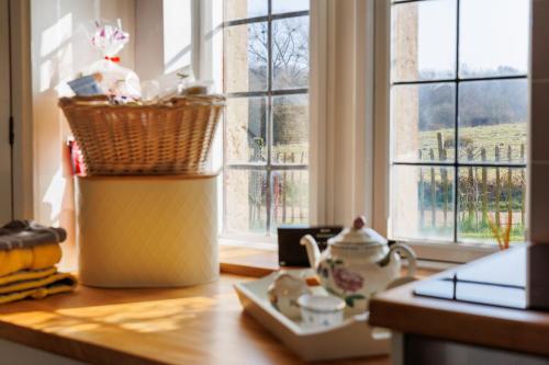a kitchen counter with a table with a basket and a window at The Old Abbey Farmhouse - Stay at Quarr Abbey Monastery - Pet-Friendly Farmhouse with History & Countryside Views, surrounded by woodland & nature in Ryde
