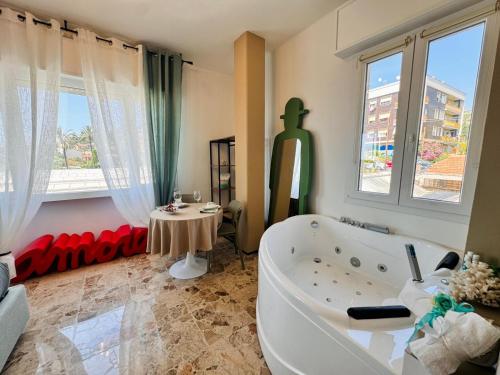 a bathroom with a tub and a table and windows at New Seaside Suite AMORE in Bordighera