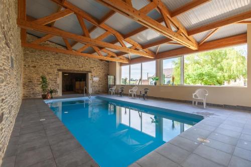 - une piscine intérieure d'eau bleue dans un bâtiment doté de plafonds en bois dans l'établissement Le Pavillon de Chasse, à Saint-Agnan-le-Malherbe