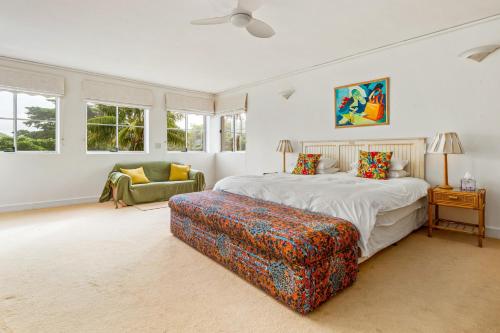 a bedroom with a bed and a chair and windows at Ocean Edge Retreat in Knysna