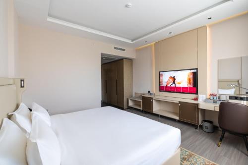 a hotel room with a bed and a flat screen tv at Mövenpick Samarkand in Samarkand