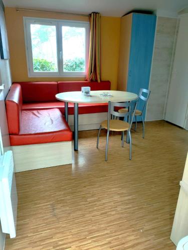 a room with a table and chairs and a couch at Mobilhome 5P proche Puy duFou 120CV in La Boissière-de-Montaigu