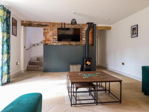 a living room with a table and a fireplace at Threshers Barn in Oswestry