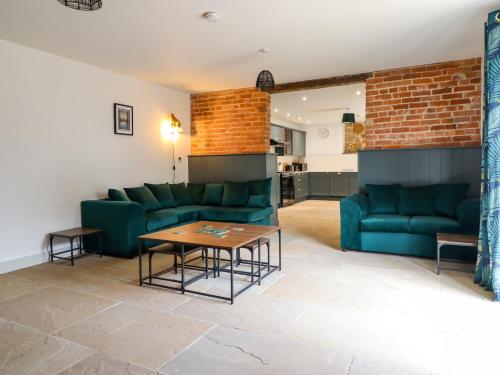 a living room with green couches and a table at Threshers Barn in Oswestry