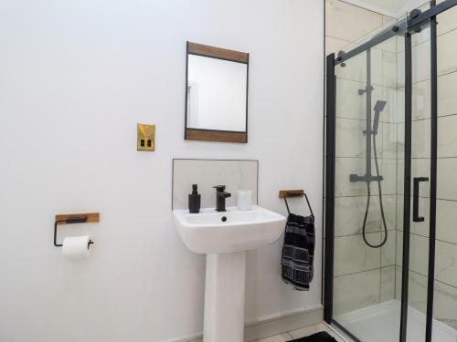 a white bathroom with a sink and a shower at Threshers Barn in Oswestry