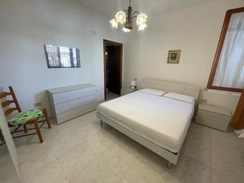 a bedroom with a bed and a chair and a chandelier at La casa di Gabry in Vada