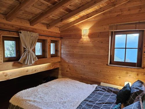 a bedroom with a bed in a log cabin at La Boutame : chalet au pied des pistes à Villard Reculas in Villard-Reculas