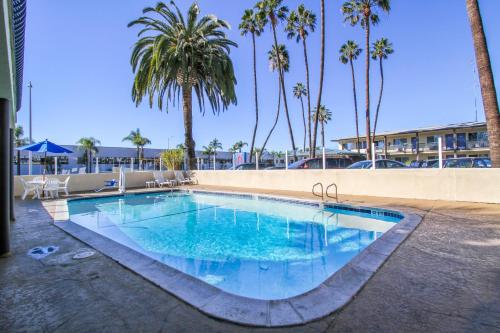 a large swimming pool with palm trees in the background at Motel 6 San Diego Airport/Harbor in San Diego