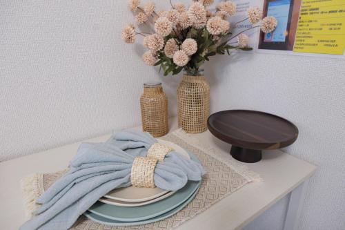 a table with a plate and a vase with flowers at Sumire in Tokyo