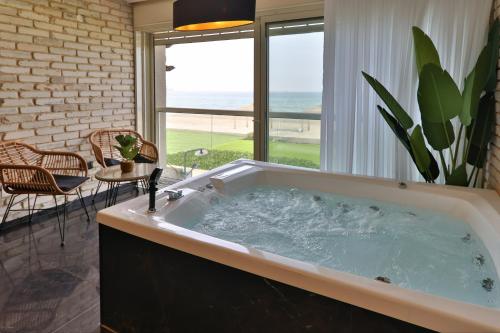 a large bath tub with a view of the ocean at שקיעה בים - דירות יוקרתיות מהממות עם ג'קוזי ונוף לים יש מקלט in Haifa