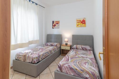 Guest House Via Acquedotto Romano في أولبيا: غرفة نوم بها سريرين ونافذة