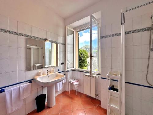 a white bathroom with a sink and a window at La casa di Martina a San Pè in Castiglione Chiavarese